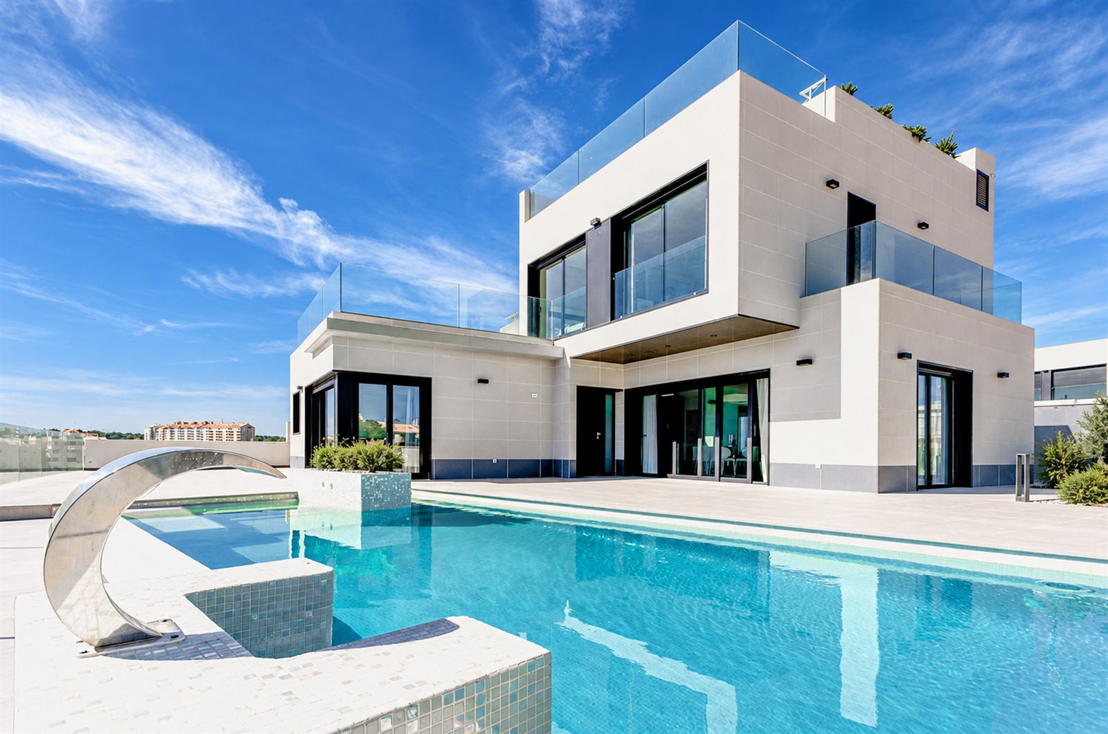 Contemporary white home overlooking a swimming pool and paved terrace